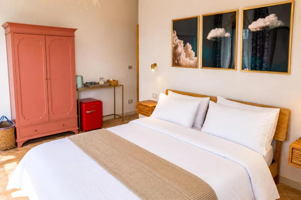 Camera 1 — il letto sotto le nuvole d'autore, con l'armadio terracotta e il frigo rosso