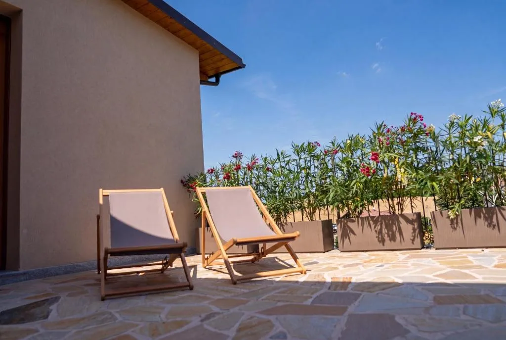 Camera 5 — la terrazza in pietra con le sdraio e gli oleandri